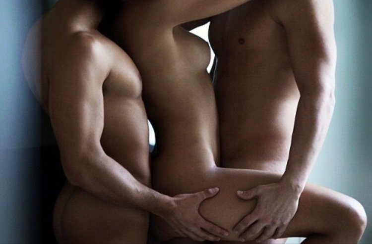 Man and two naked women hug