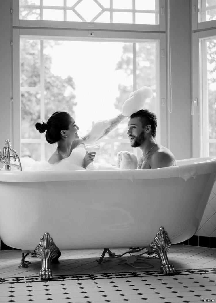 A couple in a bath by a large window